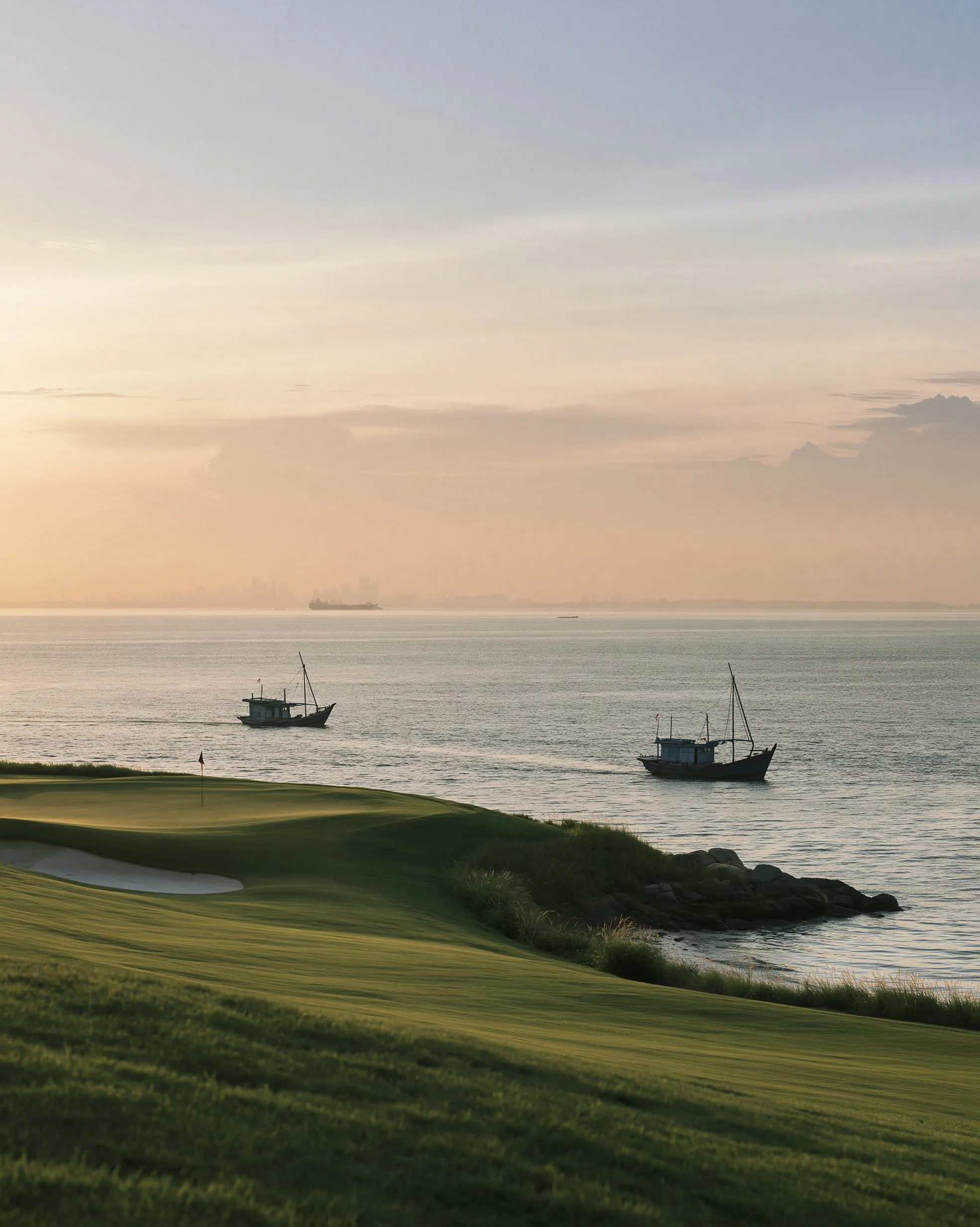 Lapangan golf di tepi teluk di Batam saat fajar dengan perahu nelayan